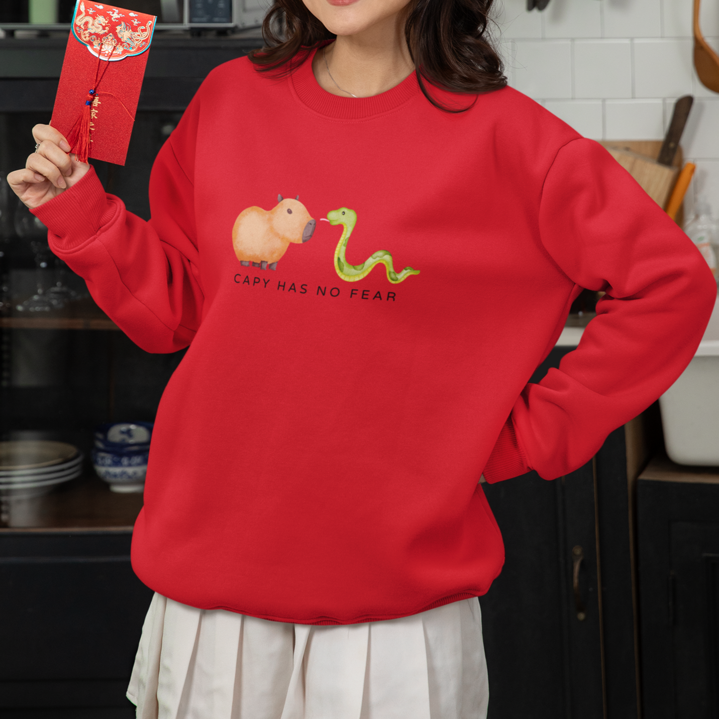 CNY Capybara clothes, Year of the Snake in style with our 'Capy has no fear' Crewneck Sweatshirt! Featuring a bold graphic of a fearless capybara facing a snake, this design is a humorous and symbolic nod to the Chinese New Year. Show off your courage and charm while staying cozy—perfect for family gatherings and festive celebrations!